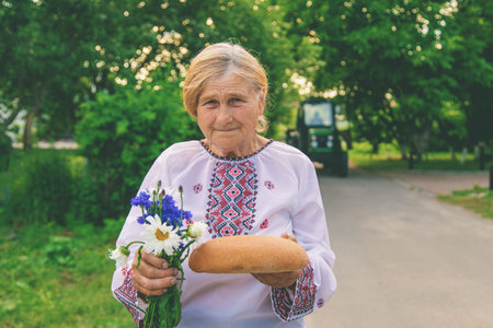 Grandmother with Ukrainian bread in her hands. Selective focus.