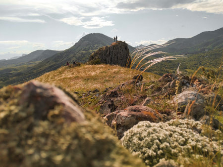 Summer landscape with a couple looking at the scenery on the rock. Travel destinations and hiking goals achievement for good health and strong bodyの写真素材