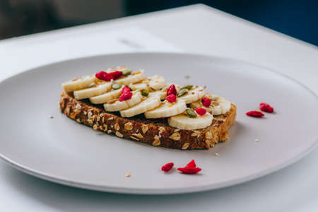 Healthy breakfast toast with chocolate peanut butter, banana, pumpkin, sunflower and flax seeds,...