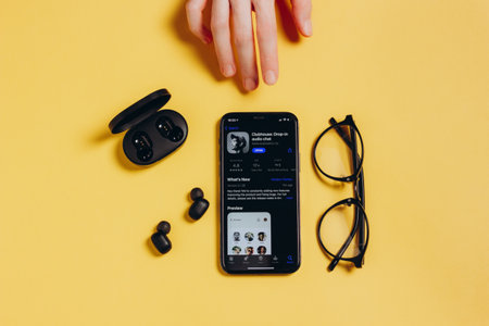 Moscow, Russia - February 16, 2021. Apple iPhone 12 Pro with Clubhouse application, headphones, glasses on yellow background of 2021. Social media appのeditorial素材