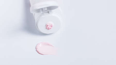Cream tube banner with pink moisturizer smear on whiteの写真素材