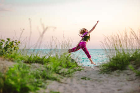 Young woman jumping on the beach towards the seaの写真素材
