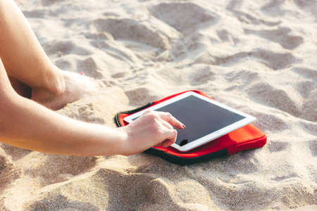 Young sporty woman using tablet on the sandy beachの写真素材