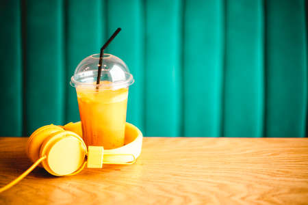 Fresh orange citrus juice with yellow headphones on tableの写真素材