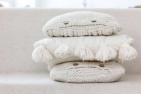 A pile of textured knitted pillows with buttons and tasselsの写真素材