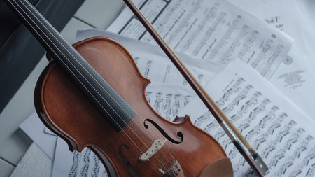 Close up detail on violin body, bow and music notes background. Classic instrument with copy space areaの写真素材