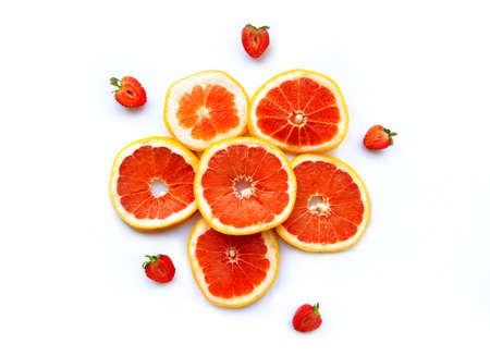 Grapefruits and strawberry on white background, top view. Citrus fruits. Slices of fresh orange. Colorful backgroundの写真素材