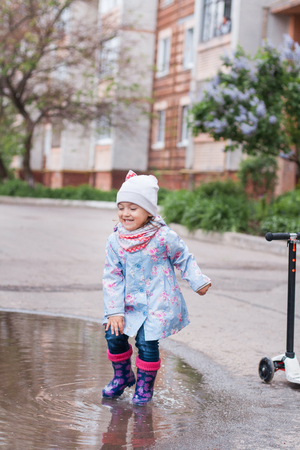 Little girl jumping in muddy puddle and smilingの写真素材