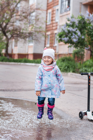 Little girl jumping in muddy puddle and smilingの写真素材