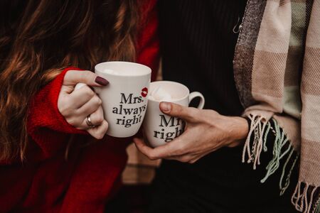 Lovers hold cups of cocoa in their handsの写真素材