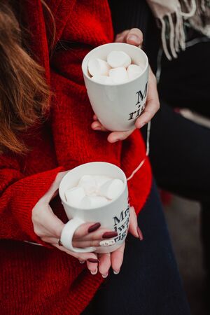 Lovers hold cups of cocoa in their handsの写真素材