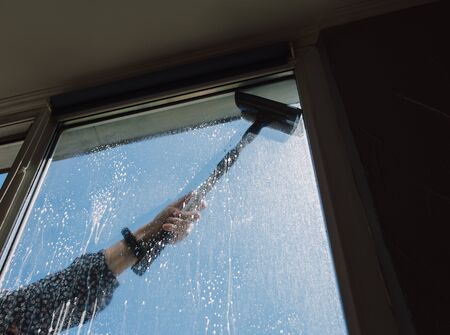 Window cleaner using a squeegee to wash a windowの写真素材