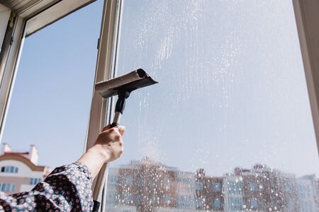 Window cleaner using a squeegee to wash a windowの写真素材