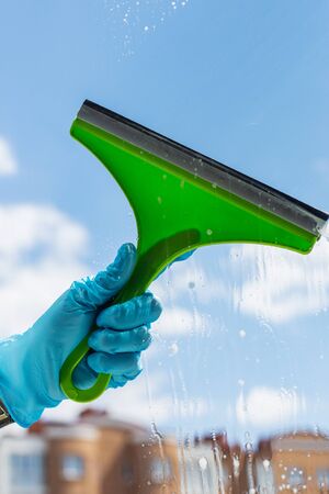 Human hand holding cleaning tool for windows on sky background. The concept of cleanliness