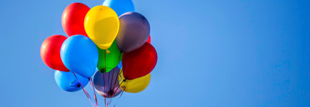Cluster of Brightly Colored Balloons Floating Against a Clear Blue Sky Concept of Celebration, Festivity, Joyful Occasions, Uplifting Moments. Banner, background with copy space.の素材