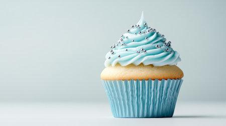 Deliciously frosted vanilla cupcake with blue icing and silver sprinkles. Concept of sweet desserts, gourmet treats, celebration food, bakery delights. Copy space.の写真素材