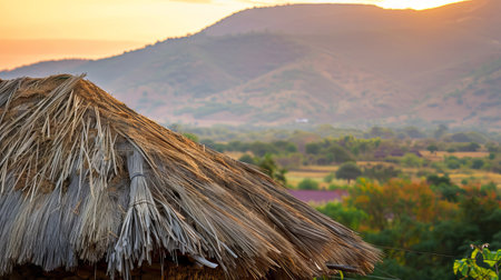 Traditional Thatched Roof Against a Picturesque Mountain Landscape at Sunset Highlighting Natural Beauty, Rustic Architecture, Tranquil Scenery, and Peaceful Countryside.の写真素材