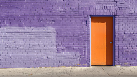 Bright Purple Brick Wall with Vibrant Orange Door on a Sunny Day. Concept of Urban Architecture, Colorful Building Design, Creative Street Art, Cityscape, Exit, Entrance. Copy space.の写真素材