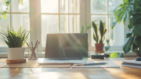 Sunlit home office desk with laptop near large windows. Concept of remote work, home office, workspace, productivity. Copy space.の写真素材