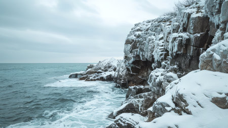 Snowy coastal cliffs with icy formations along a foggy seascape. Concept of winter landscape, nature, cold weather, seashore tranquility.の写真素材