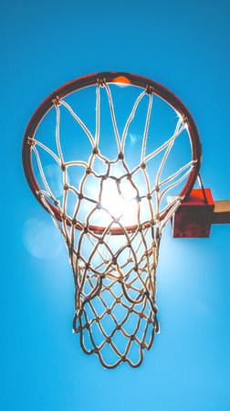 Basketball hoop with net against a blue sky in sunlight. Concept of sports equipment, basketball...