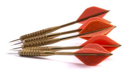 Golden darts with red flights isolated on a white background. Concept of leisure game, precision, sports hobby, fun activity.の写真素材
