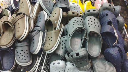 Dnipro, Ukraine - April 26, 2025 - Assortment of casual rubber clogs with ventilation holes stacked in supermarket basket. comfortable footwear, Crocs, summer shoes, lightweight casual style.のeditorial素材