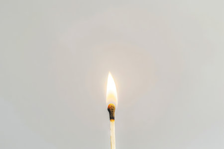 Single burning matchstick against a clean white background. Concept of ignition, heat, energy, simplicity, and minimalism. Copy space.の写真素材