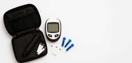 Diabetic kit essentials featuring glucose meter, test strips, and lancing device on white background. health management, diabetes care, medical supplies, everyday necessity, Banner, copy space.の写真素材