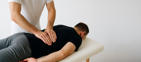 Caucasian man receiving a manual therapy session in a simple spa setting for relaxation and wellness. concept of therapeutic massage, chiropractic care, self-care, Wide banner, copy space, white background.のeditorial素材