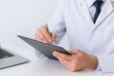Close-up of caucasian doctor writing on clipboard in professional medical office. concept of healthcare documentation, medical professional, office work.の写真素材