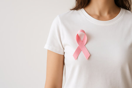 Caucasian woman wearing pink ribbon t-shirt to show support against cancer. concept of breast cancer awareness, symbol of hope, solidarity with survivors, copy space, white background.の写真素材