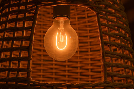 Warm glow of a cozy wicker lamp illuminating a simple rustic space with soft lighting and comforting atmosphere. concept of relaxation, home lighting, rustic decor.の写真素材