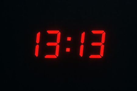 Digital clock display showing 13:13 in minimalist red light on black background. concept of...