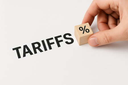 Hand holding wooden block with percentage symbol next to tariffs text. concept of economic policy,...