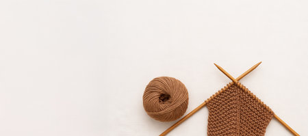 Knitting and cozy vibes with ball of yarn and knitting needles on neutral background. concept of handcrafting, serenity, creative hobby.の写真素材