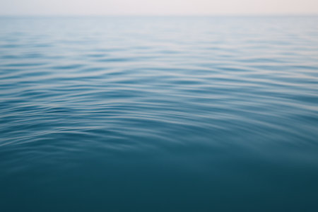 Calm ocean waves gently rippling on tranquil water surface under clear blue sky. concept of serenity, marine peacefulness, natural relaxation scene.の写真素材