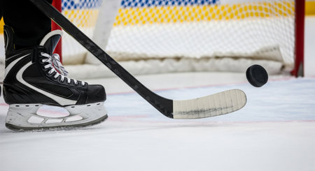 Close-up of hockey player hitting puck with stick on ice rink. concept of sports action, athletic performance, precision.の写真素材