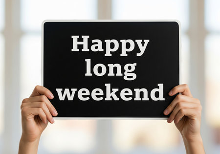 Woman holding a black sign with inscription happy long weekend. Holiday celebration concept for extended break or vacation..の写真素材