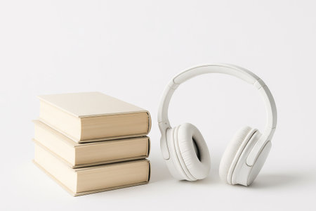 Stack of classic books with white headphones on minimalist white background. concept of reading,...