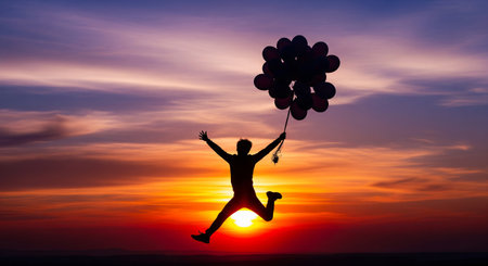 Man jumping with balloons at sunset. Freedom and happy concept. Creative idea for cheerful and joyful advertising and celebration..の写真素材