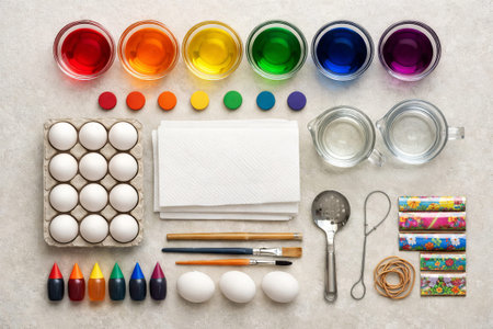 Easter egg dyeing supplies including white eggs, rainbow colors, brushes, and glasses on a table....