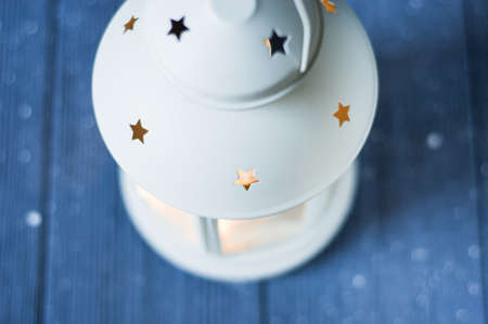 White vintage Lantern with burning candles, pine cones on wooden table and glitter lights background. Christmas background. happy New Year. Selective focus holidey.の写真素材