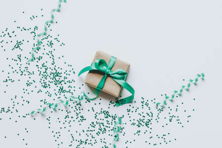 Gift box over star shaped golden sequins on a white background. Storage and order concept.