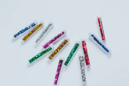 Small glass bottles or jars with sealed corks with multicolored shiny stars stand in a row on a pink...
