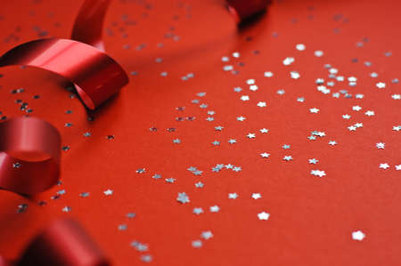 Red ribbon and glitter stars on a red background.の写真素材