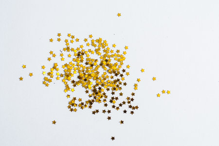Festive golden stars of confetti on a white background.