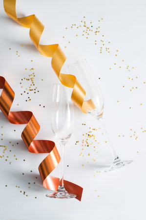 Happy New Year composition. Champagne glasses with gold confetti stars and drinking straws on white table background. Party concept. Flat lay, top view.の写真素材