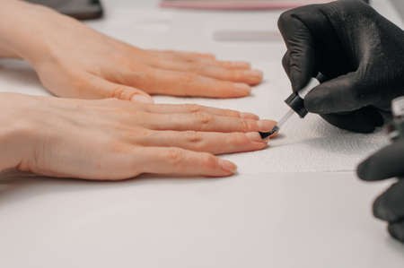 Manicurist filing clients nails at table, closeup. Spa treatment. Beautician filing female clients nailsの写真素材