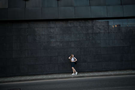 teenage girl with a backpack on the background of a large gray buildingの写真素材